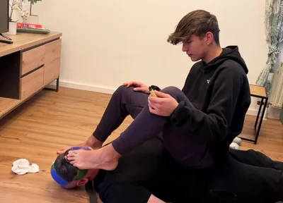 German master sitting on feet licking boy